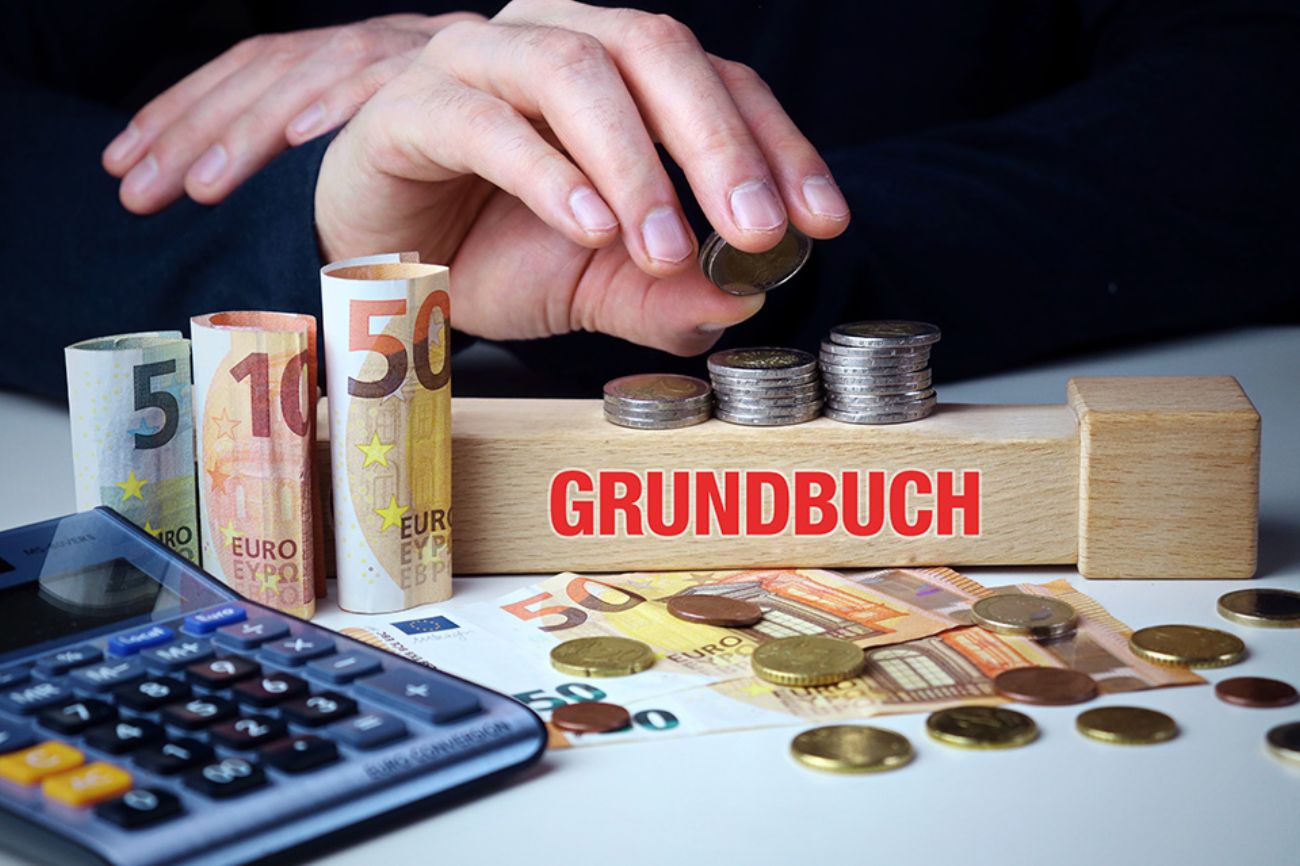 Foto: Grundbuch, Taschenrechner und Geld